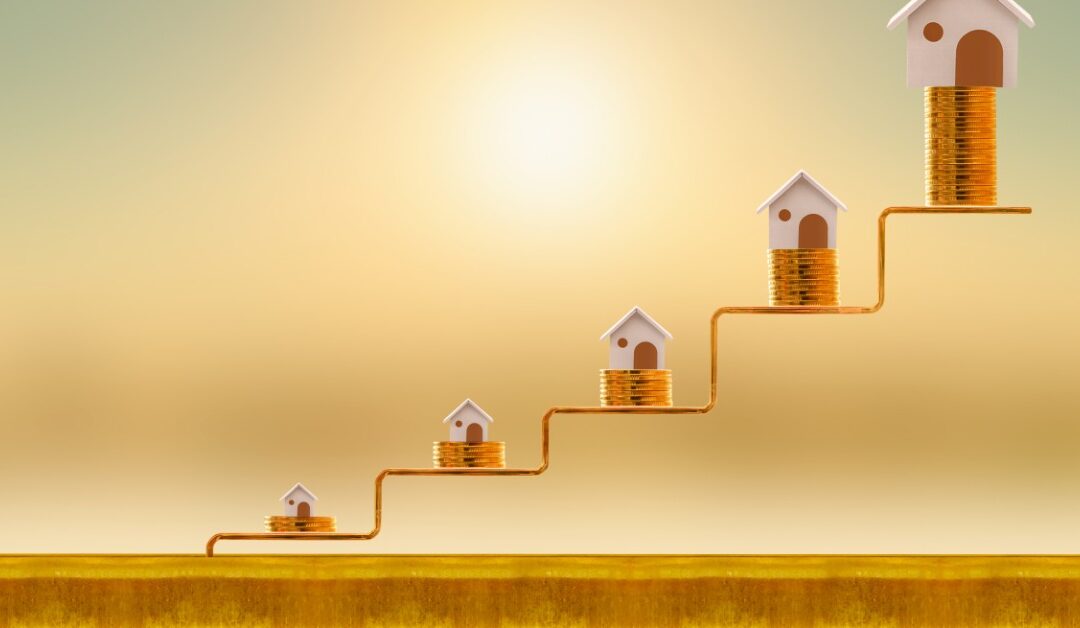 Miniature houses sit on piles of coins arranged in increasing height. The coins are on a staircase-like structure.