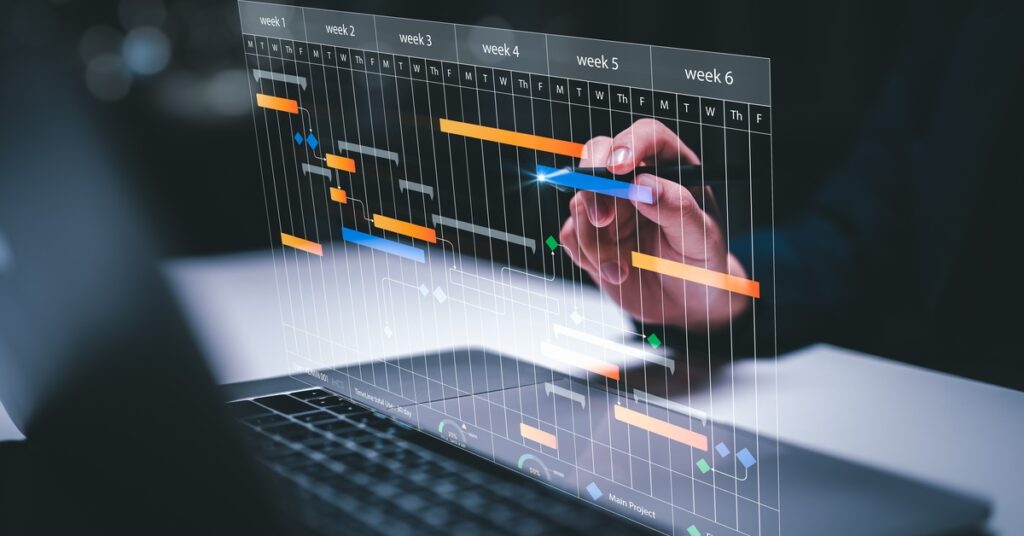 A semi-transparent digital schedule appears above an open laptop. It shows colored bars stretching across several weeks.