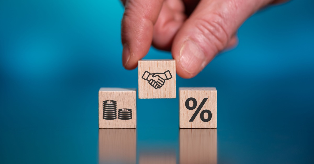 A hand places a cube with a handshake icon between two other cubes. One shows stacked coins, the other a percent symbol.