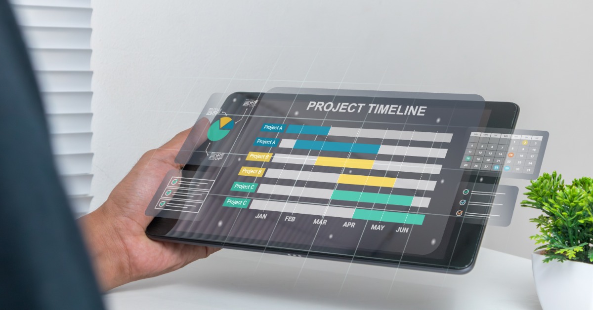 A person holds a digital tablet displaying a project timeline chart with colored bars for different projects and months.