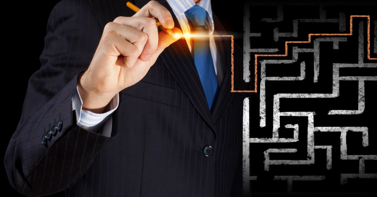 A 2-D illustrated maze is in the foreground. Behind it, a person in a suit draws a line that goes out of the maze.