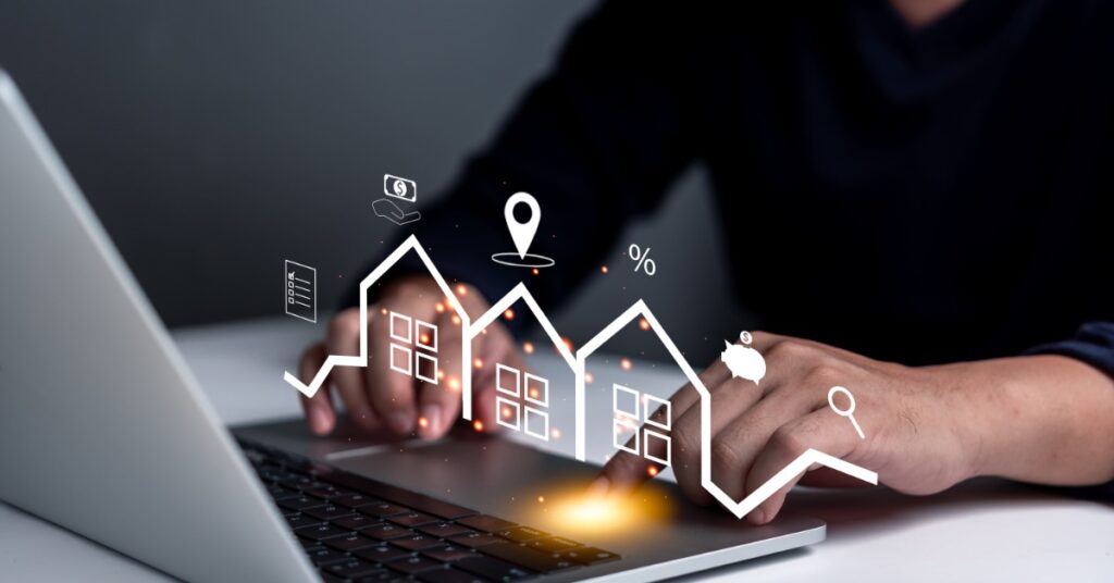 A person uses a laptop. A digital image of outlined houses and financial and real estate icons is above the keyboard.