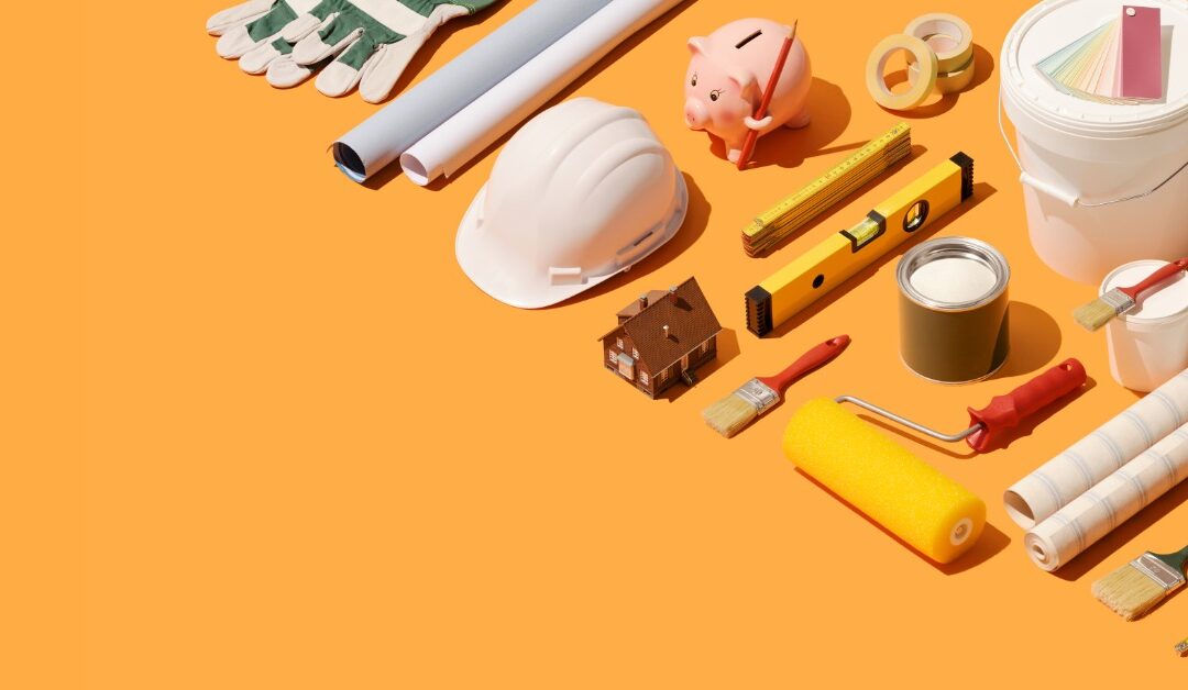 A piggy bank holding a pencil is between renovation tools and supplies arranged on an orange background.