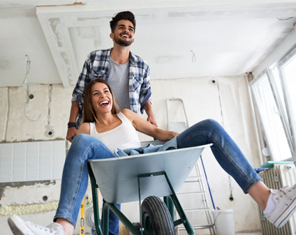 Man pushing women in wheelbarrow for fun in renovated house project